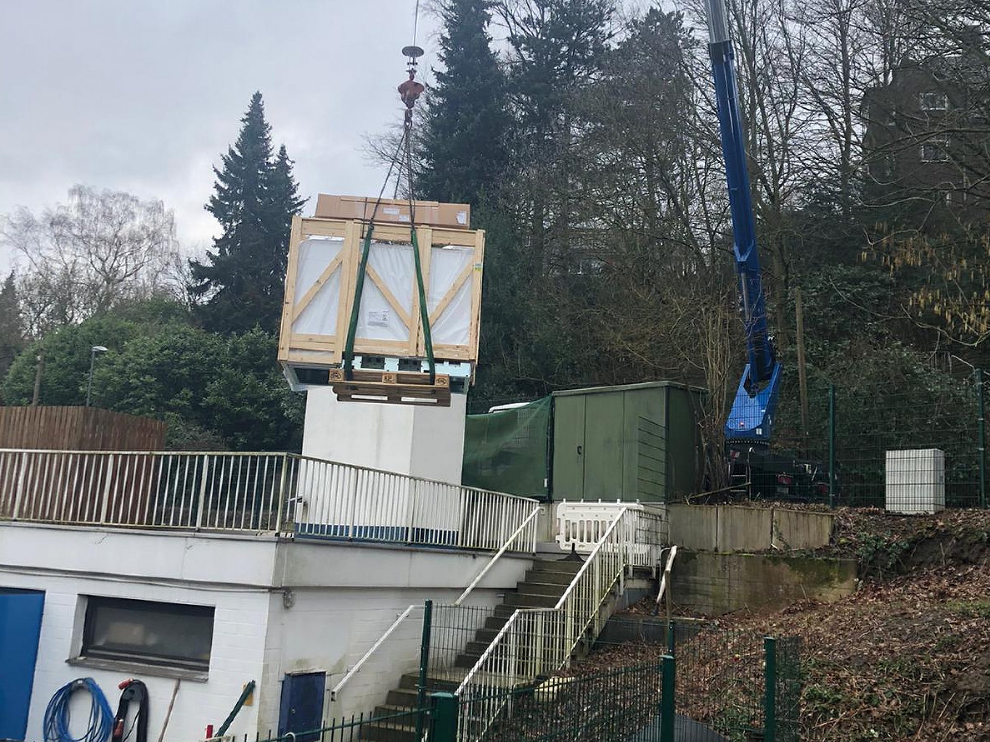 Die neuen Heizkessel werden mit dem Kranwagen über das Gebäude gehoben